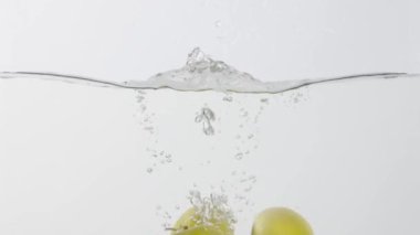 Taze elmaların hafif arkaplana doğru suya düşmesi