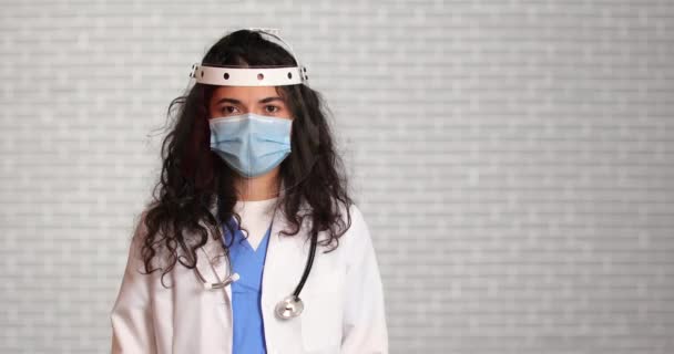 Dokter Met Medisch Masker Gezichtsscherm Tegen Lichte Achtergrond — Stockvideo
