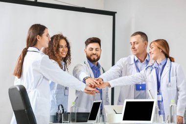 Modern klinikteki toplantı sırasında doktorlar el ele tutuşuyor.