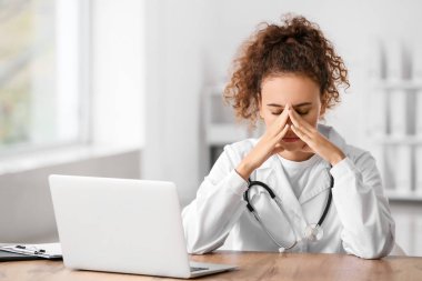 Stresli kadın doktor klinikte masada oturuyor.