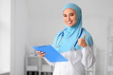 Klinikte baş parmak gösteren Müslüman kadın doktor portresi
