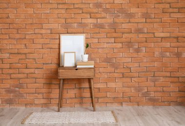 Boş çerçeveli masa ve tuğla duvarın yanında kitaplar