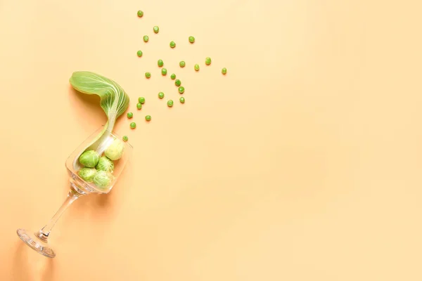 Composition with glass and fresh vegetables on color background