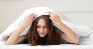 Yatakta battaniyenin altında yatan komik genç bir kadının sabahı