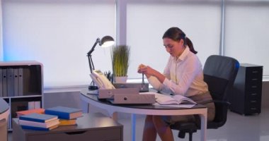 Genç iş kadını gece geç saatlerde ofiste eğleniyor ve telefona cevap veriyor.