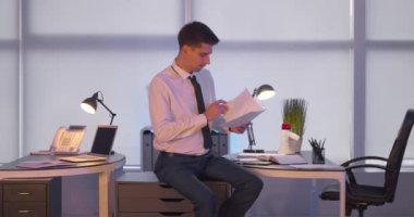 Ofiste sandalye süren ve dergi okuyan tembel meslektaşına beşlik çakan meşgul bir adam.