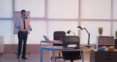 Genç adam mesai bitiminde ofiste futbol oynuyor.