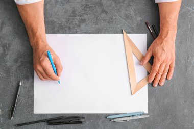 Koyu arkaplan üzerinde kalem ve cetvel olan boş kağıt kağıtlı erkek eller.