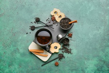 Bir fincan siyah çay, arkaplanda kuru yapraklar ve baharatlar