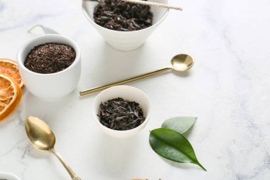 Kuru siyah çay yaprakları ve hafif arka planda kaşıklar.