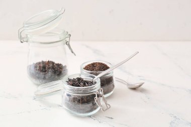 Kavanoz kuru siyah çay ve kaşıkla aydınlık arka planda