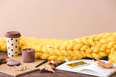 Masada örülmüş ekose, kitap ve cep telefonu ile sonbahar kompozisyonu