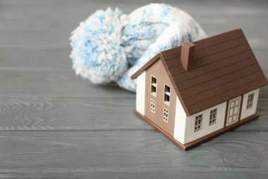 Masanın üzerinde ev ve sıcak şapka figürü. Isınma mevsimi kavramı
