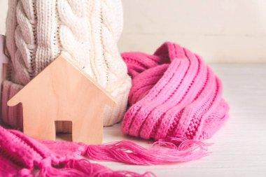 Masanın üzerinde ev ve kalın giysiler var. Isınma mevsimi kavramı