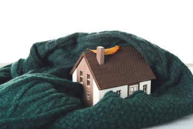 Beyaz arka planda masa üzerinde ev ve sıcak eşarp figürü. Isınma mevsimi kavramı