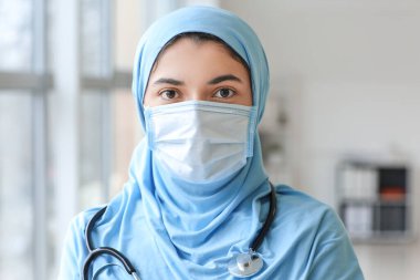 Klinikte koruyucu maske takan kadın Müslüman doktor portresi