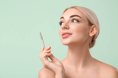 Genç bir kadın kaşlarını düzeltiyor.