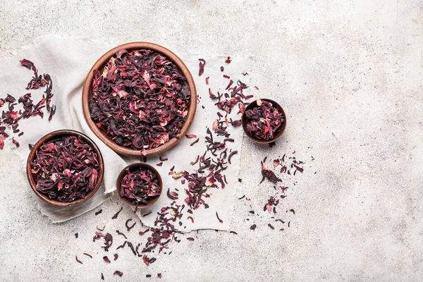 Bowls with dry hibiscus tea on grunge background