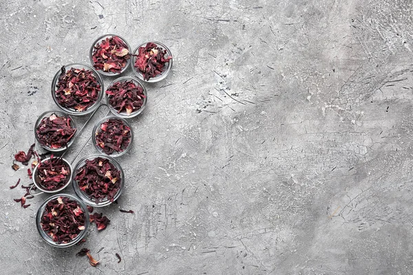 Bowls with dry hibiscus tea on grunge background