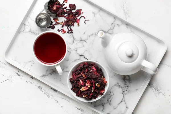 Tray with dry hibiscus tea on light background