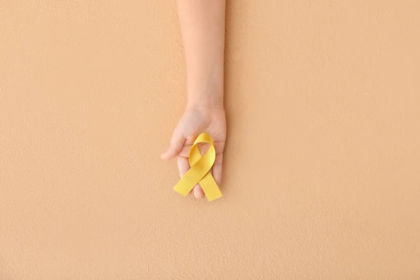 女性手持有黄色丝带在颜色背景癌症概念 图库照片 C Serezniy