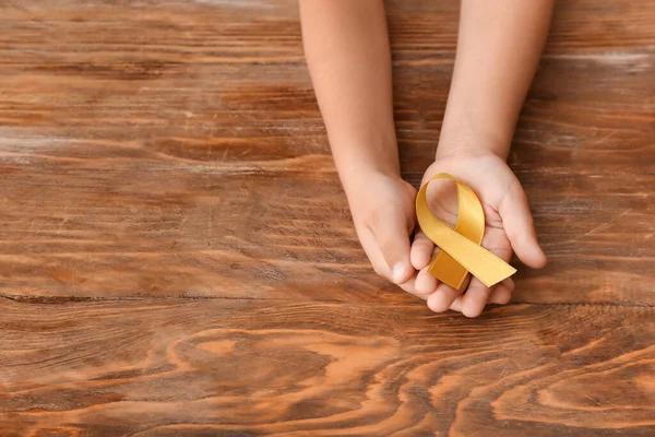 Mãos Criança Com Fita Dourada Fundo Madeira Conceito Consciência Câncer — Fotografia de Stock