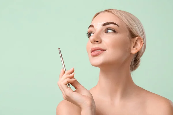 Mujer Joven Corrigiendo Sus Cejas Sobre Fondo Color — Foto de Stock