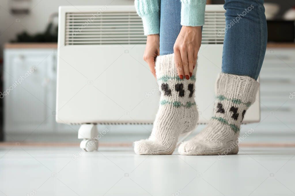 Woman wearing knitted socks at home. Concept of heating season