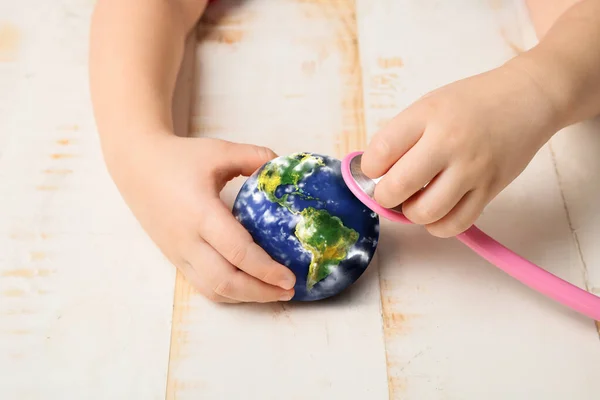 Mãos Criança Com Estetoscópio Modelo Terra Sobre Fundo Madeira Branca — Fotografia de Stock