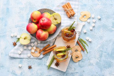 Renkli kavanozlarda baharat ve elma dilimleri olan lezzetli bir içecek.