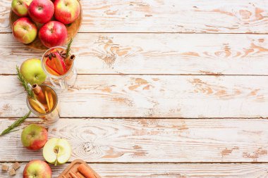 Baharatlı lezzetli bir içecek ve ahşap arka planda elma dilimleri.
