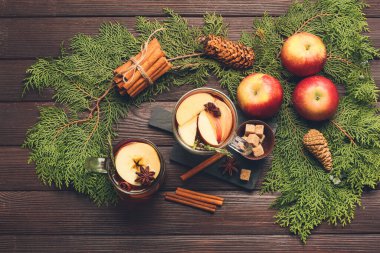 Baharatlı lezzetli bir içecek ve ahşap arka planda elma dilimleri.