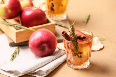 Baharatlı ve arkaplanda elma dilimleri olan lezzetli bir içecek.