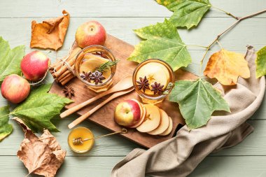Baharatlı lezzetli bir içecek ve ahşap arka planda elma dilimleri.