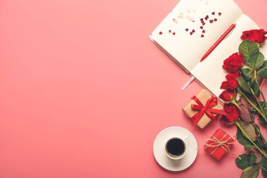 Gül çiçekli hediyeler, not defteri ve renkli arka planda bir fincan kahve
