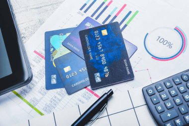 Masada hesap makinesi, tablet bilgisayar ve belge bulunan kredi kartları