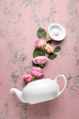 Renkli arkaplanda çaydanlık ve güllerle kompozisyon