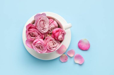 Arka planda pembe güller olan bir fincan.