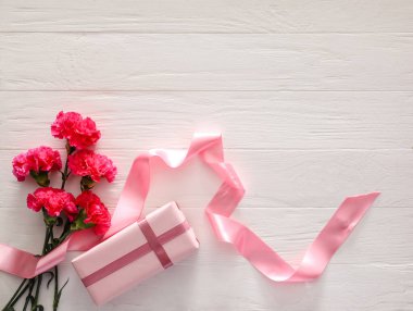 Bir buket güzel çiçek ve beyaz ahşap arka planda hediye.