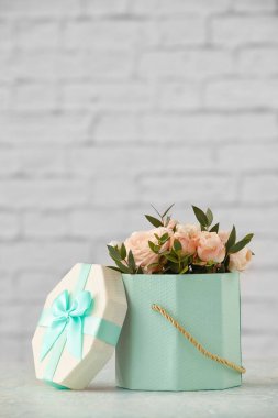 Masanın üzerinde güzel çiçekler olan hediye kutusu.
