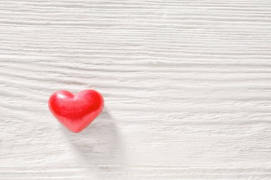 Beyaz ahşap arka planda kırmızı kalp