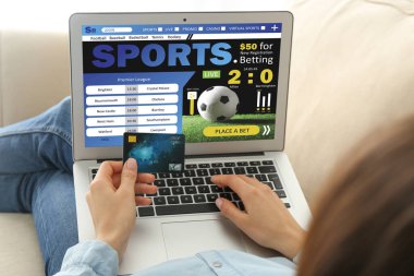 Kredi kartı olan genç bir kadın evde spor bahisleri oynuyor.