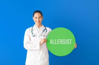 Portrait of female doctor holding poster with text ALLERGIST on color background clipart