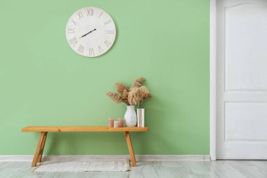 Odasında renk duvarı olan saat ve ahşap bank.