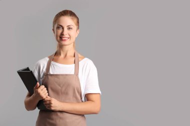 Gri arka planda menü tutan genç kadın