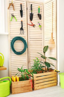 Ahırın duvarında farklı bahçe malzemeleri asılı.