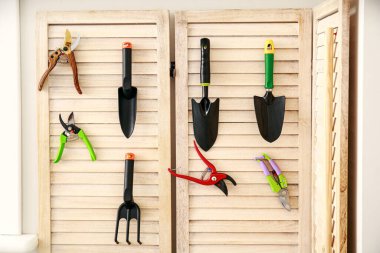 Ahırın duvarında farklı bahçe malzemeleri asılı.