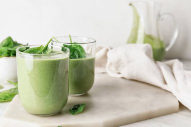 Hafif arka planda bir bardak sağlıklı ıspanaklı smoothie.