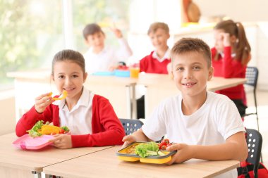 Öğrenciler sınıfta sağlıklı öğle yemeği yiyor.