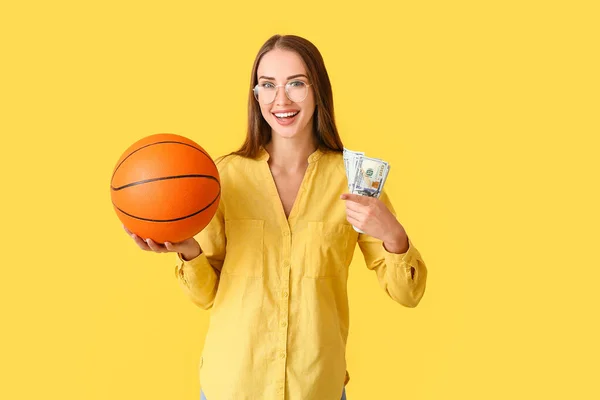 色の背景にボールとお金を持つ美しい女性 スポーツベットの概念 — ストック写真